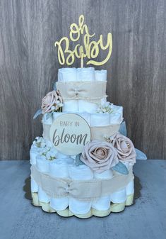 a three tiered diaper cake decorated with flowers and the words baby in bloom