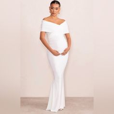 a pregnant woman in a white gown posing for the camera with her hands on her hips