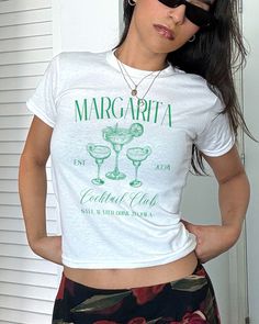 Margarita Club Baby Tee, Coquette Shirt, Margarita Shirt, Vintage Tee, Y2K Aesthetic, Cocktail T shirt, Coquette Top, Marg Time, Tequila *IMPORTANT PLEASE READ BEFORE PURCHASING* My store uses DTG (Direct to Garment) printing. This means the design is printed into the garment. This means it is designed to last longer than other printing processes. Due to this printing process the design colors may not be as vibrant as shown in the photos. There may at times be a slight difference between real an Fitted Short Sleeve Top With Screen Print, Cute Fitted Tops With Text Print, Fitted White Printed Tops, Fitted White T-shirt With Funny Print, Cute Green Printed Top, Casual Fitted Screen Print Tops, Fitted Summer Tops With Funny Print, Fitted Top With Funny Print For Summer, Cute Fitted Printed Top