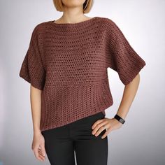 a woman in black pants and a brown sweater is standing with her hands on her hips