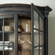 an old fashioned china cabinet with glass doors and shelves filled with books, knick - knacks and baskets