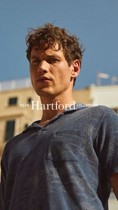 a young man standing in front of a building with his head turned to the side