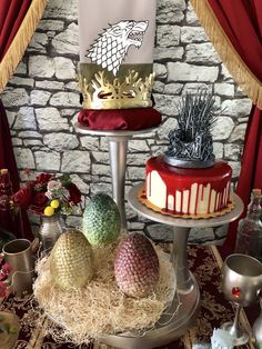 three tiered cakes on display in front of a stone wall and red drapes