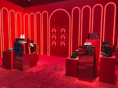 a room filled with red lighting and lots of different types of shoes on pedestals