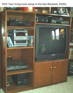 a tv sitting on top of a wooden entertainment center next to a bookcase filled with books