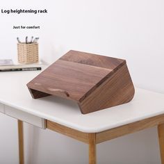 a wooden tray sitting on top of a white table next to a book and pen holder