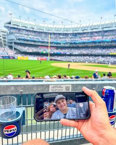 a man taking a photo with his cell phone at a baseball game in the stadium