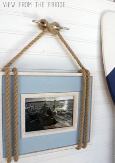 an old photo hangs on the wall next to a surfboard with rope hanging from it