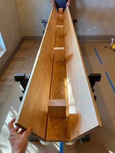 a man standing on top of a wooden table next to another person holding a piece of wood