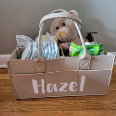 a teddy bear sitting in a basket filled with diapers and personal care items on the floor