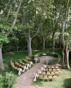 an outdoor ceremony set up in the middle of a park with lots of chairs and tables