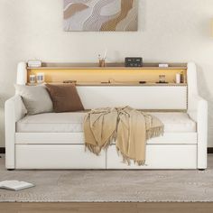 a living room with a white couch and a painting on the wall above it's headboard