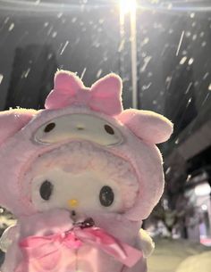 a hello kitty stuffed animal with a pink bow on it's head in the snow