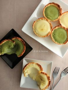 four small pies with green filling on white plates next to silverware and fork