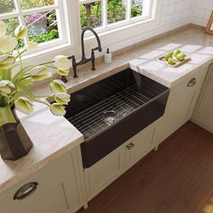 a black kitchen sink sitting under a window next to a vase with flowers in it