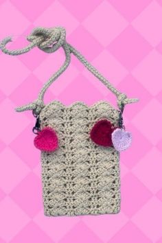 a crocheted purse with two pom - poms hanging from it