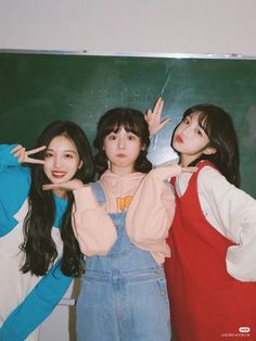 three girls standing in front of a blackboard with their hands up to the side