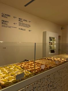 an assortment of pizzas on display in a store window with price signs behind them