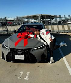 a man leaning on the hood of a car with a red bow tied around it