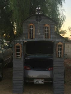 a car is parked in front of a shed with two windows and an open trunk