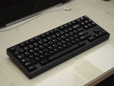 a black computer keyboard sitting on top of a desk next to a mouse and monitor