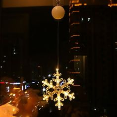 a snowflake ornament hanging from the ceiling in front of a window