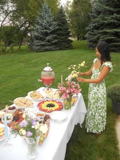 a woman standing in front of a table filled with food