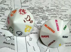 two white dices with colorful writing on them sitting on top of a world map