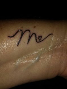 a woman's wrist tattoo with the letter m on it