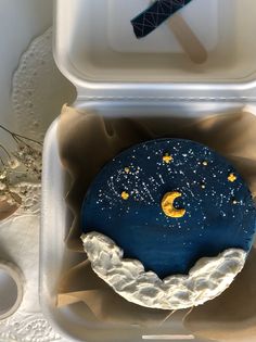 a blue and yellow decorated doughnut in a plastic container