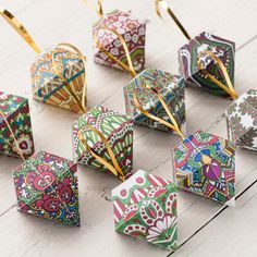 colorful origami ornaments are arranged on a white table with gold pins in them