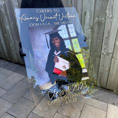 a glass plaque with the image of a woman in graduation gown holding her diploma and posing for a photo