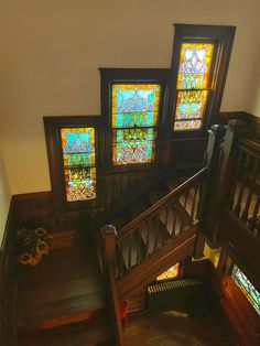 three stained glass windows on the side of a staircase leading up to a second floor