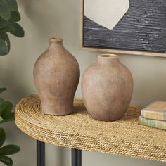 two vases sitting on top of a wicker table next to a potted plant