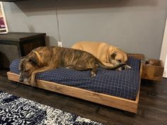 two large dogs laying on top of a dog bed in a room with hardwood floors