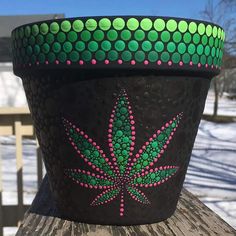 a potted plant with green and pink dots painted on it's side in the snow