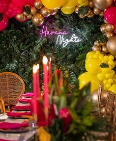 a decorated table with candles and balloons in the background