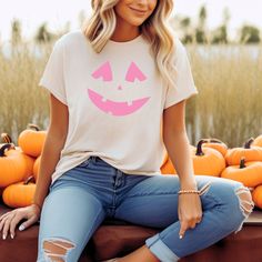 a woman sitting on top of a crate filled with pumpkins wearing a t - shirt