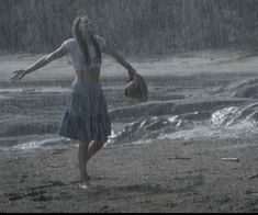 a woman standing on top of a sandy beach in the rain