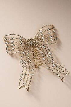 a gold hair comb with pearls on it's sides and a bow at the top