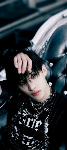 a young man with black hair and piercings sitting on a leather chair