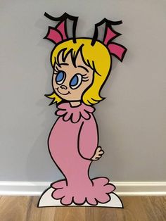 a cardboard cutout of a cartoon character with blue eyes and blonde hair, sitting on top of a wooden floor