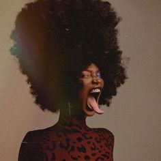 a woman with her tongue out and an afro hairdo is posing for the camera