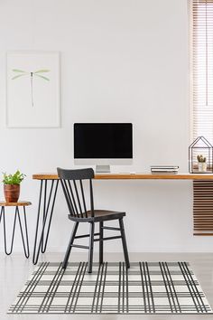 a desk with a computer on top of it and two chairs next to it in front of a window