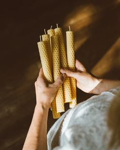 a person holding four yellow candles in their hands