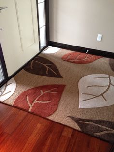 an area rug with leaves on it in front of a door