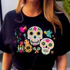 a woman wearing a black t - shirt with colorful sugar skulls on it