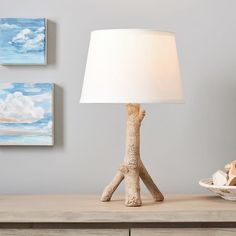 a table lamp sitting on top of a wooden dresser next to a bowl and plate