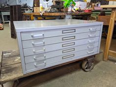 a metal filing cabinet sitting on top of a wooden pallet in a garage next to a workbench