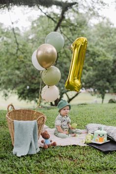 a baby is sitting in the grass with balloons